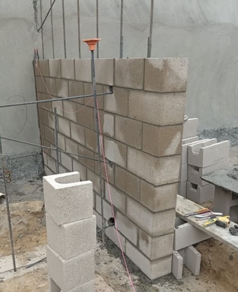 Cinderblock wall under construction, showcasing the building process with rebar supports and tools on-site